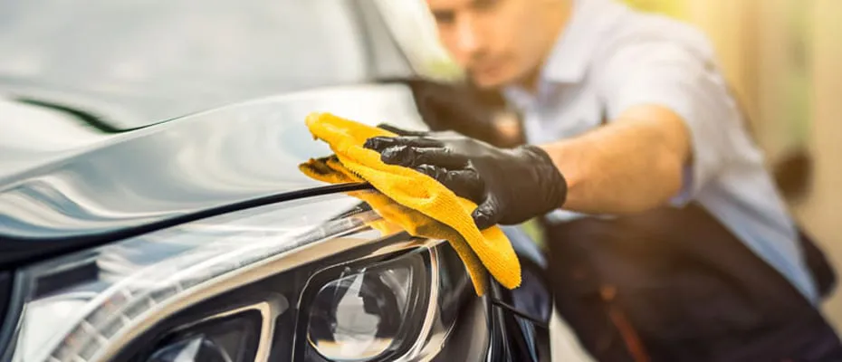 Ein Mann poliert die Front eines Autos