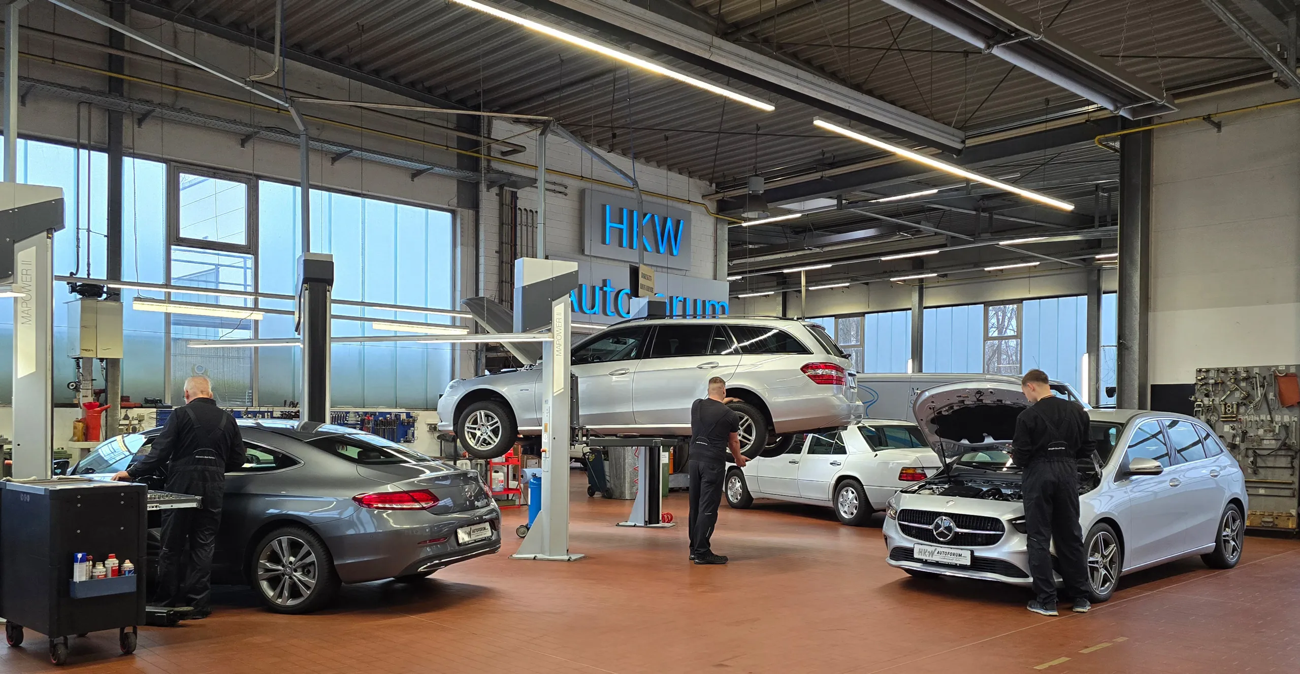 Blick in die Werkstatt, wo gerade an mehreren Fahrzeugen gearbeitet wird.